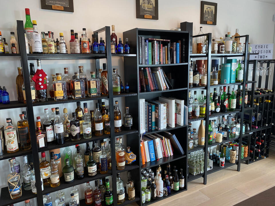 A photo of our home bar, with 10 mostly-full shelves and 150-200 different bottles of spirits, liqueurs, and other cocktail ingredients